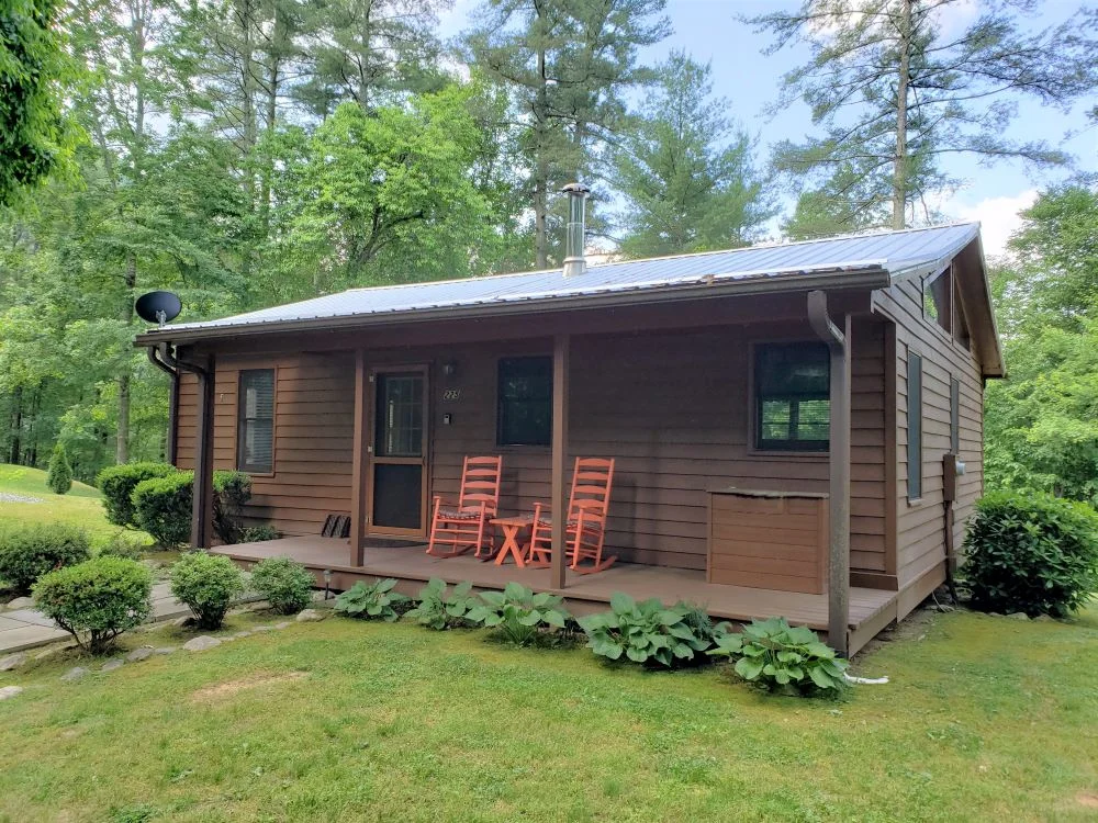 Cabin in the woods with orange rocking chairs on the porch